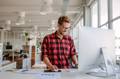 Smiling entrepreneur working at a desktop computer in a bright modern office