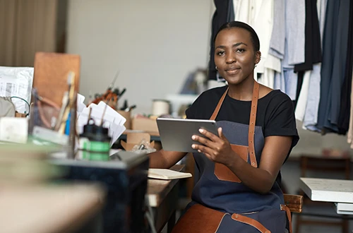 Confident female small business owner using a tablet in her workshop